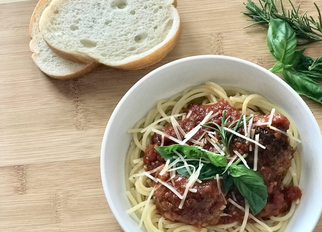 Marinara over pasta with shaved Parmesan Cheese and bread slices