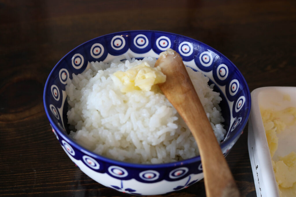 blue bow of rice with a pat of butter and a wooden knife