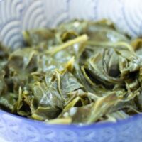 cooked collard greens in a blue and white patterned bowl.