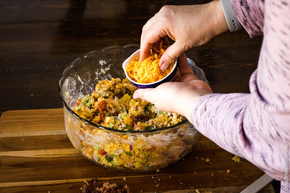 adding cheese to bacon cornbread salad