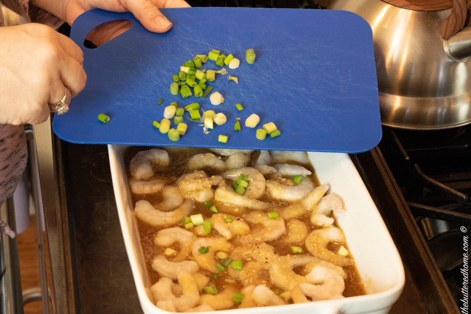 adding green onions to spicy bbq shrimp
