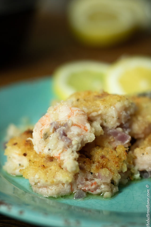 close up of crunchy baked shrimp on blue plate with lemon wedges
