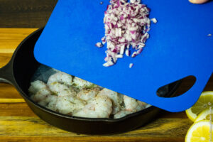 adding diced red onions to shrimp