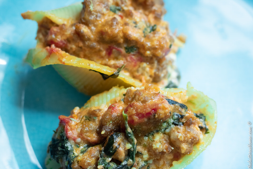 sausage and spinach stuffed shells on a blue plate