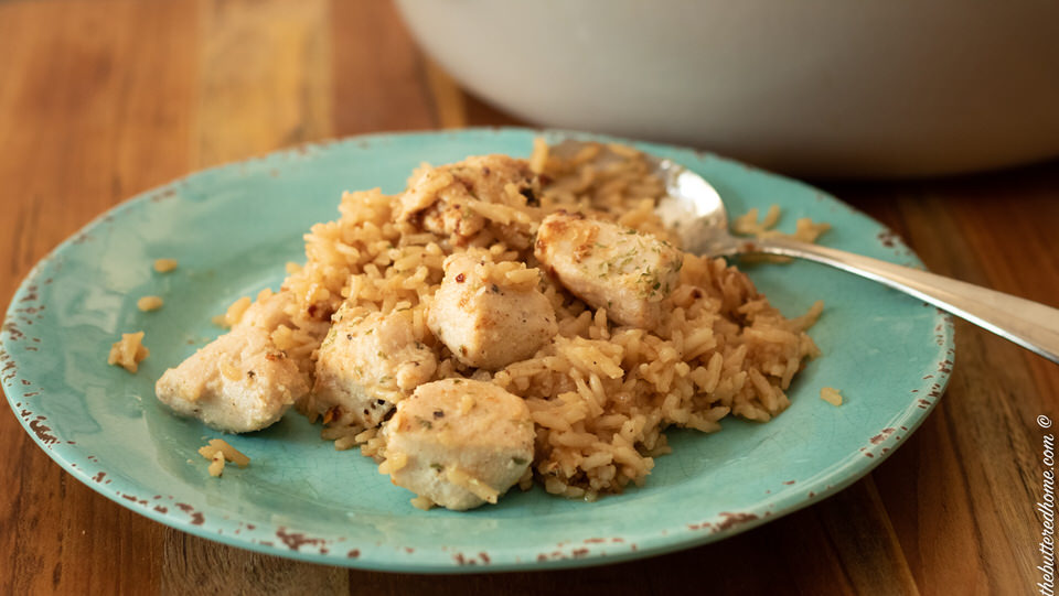 close up of skillet chicken and rice on a blue plate with a silver spoon