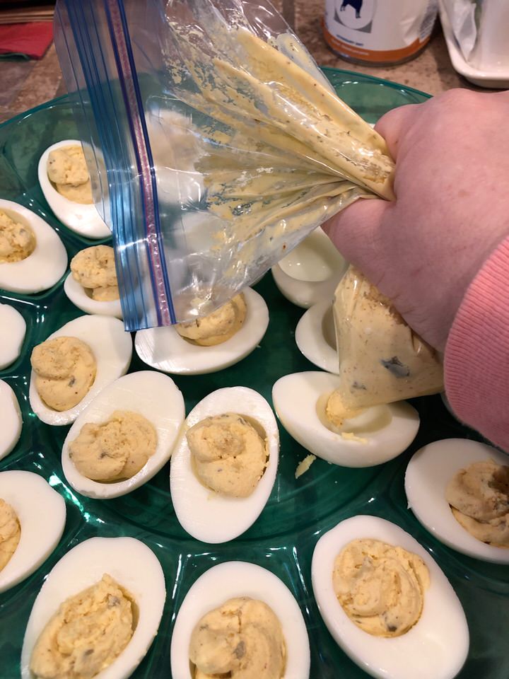 squeezing the yolk mixture out of the bag into the white bases of eggs