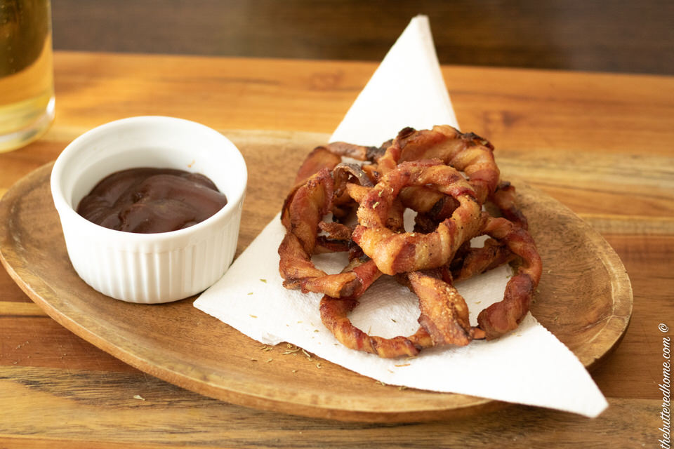 bacon wrapped onion rings cooked and browned with a side of bbq sauce