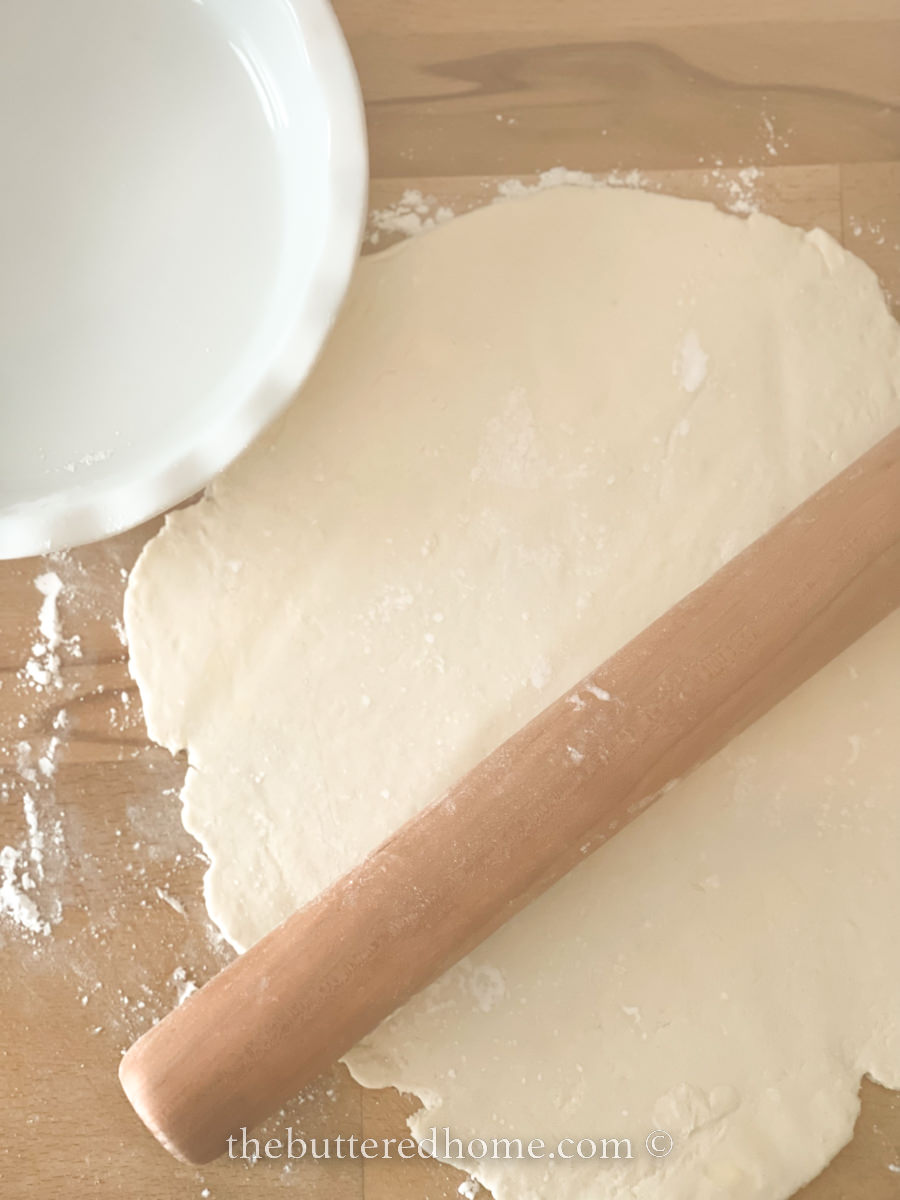 homemade pie crust being rolled out on a floured board