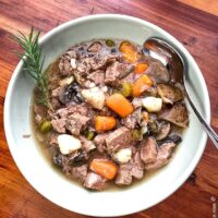 bow of instant pot rosemary beef stew with a fresh sprig of rosemary