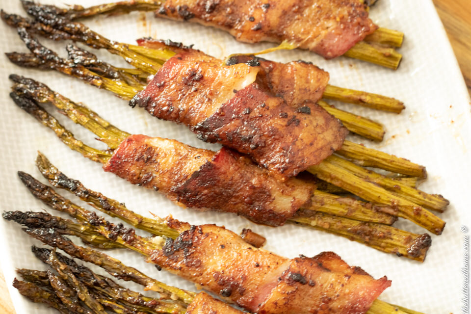 baked bacon wrapped asparagus on a gray plate