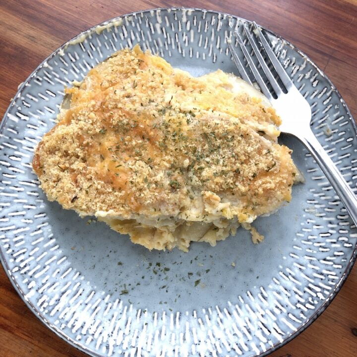Scalloped potatoes and onions on a blue plate with a silver fork
