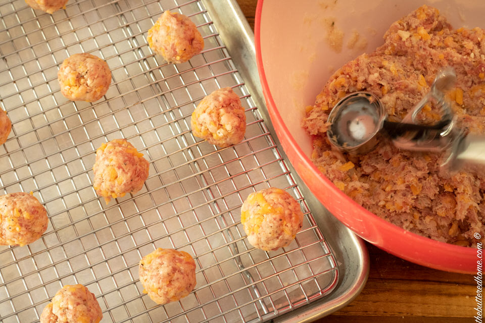 rolle sausage balls on a baking sheet with a rack
