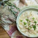 Chicken and dumplings in a green bowl with a silver spoon
