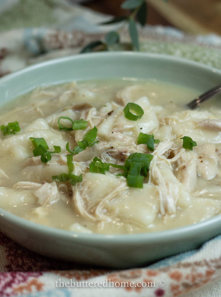 Chicken and dumplings in a green bowl with a silver spoon
