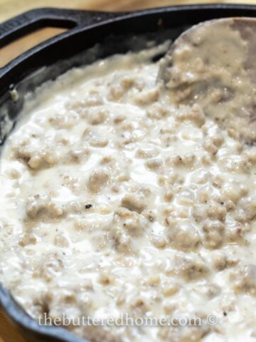 sausage gravy being spooned up on a wooden spoon