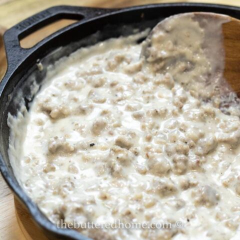 sausage gravy being spooned up on a wooden spoon
