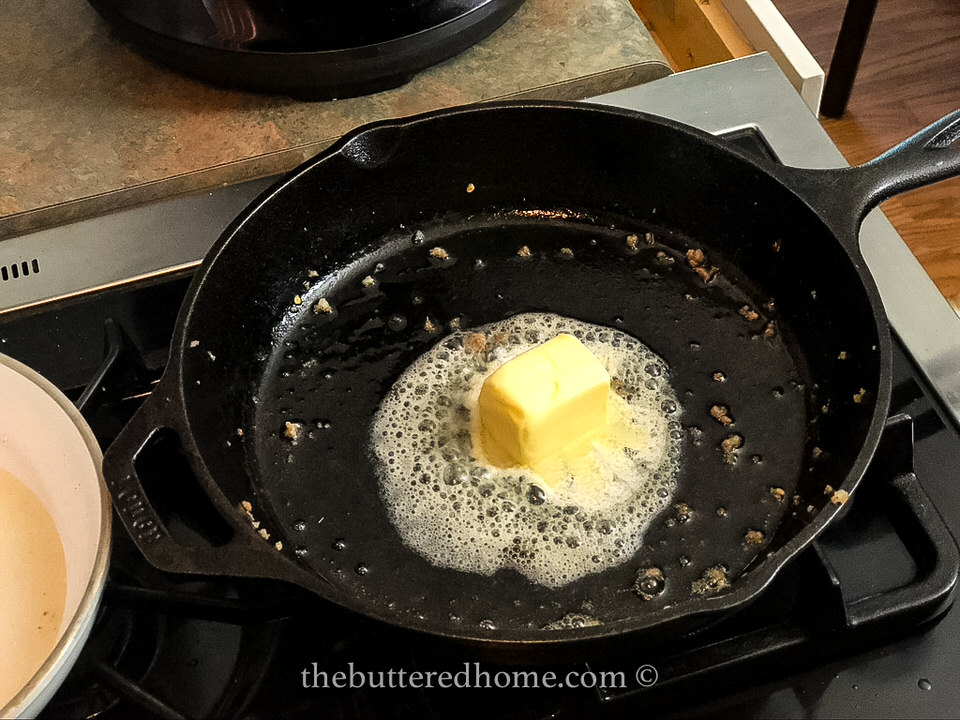 melting butter in a cast iron pan with sausage drippings