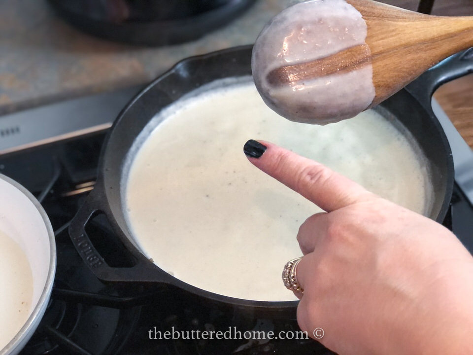 testing the thickness of the gravy with a wooden spoon