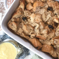 Bread pudding in white dish with bourbon sauce on the side