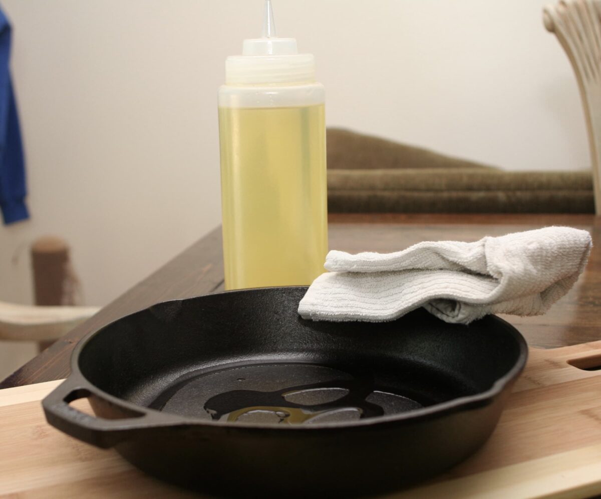 Seasoning the skillet with oil. Bottle of oil is in the background.