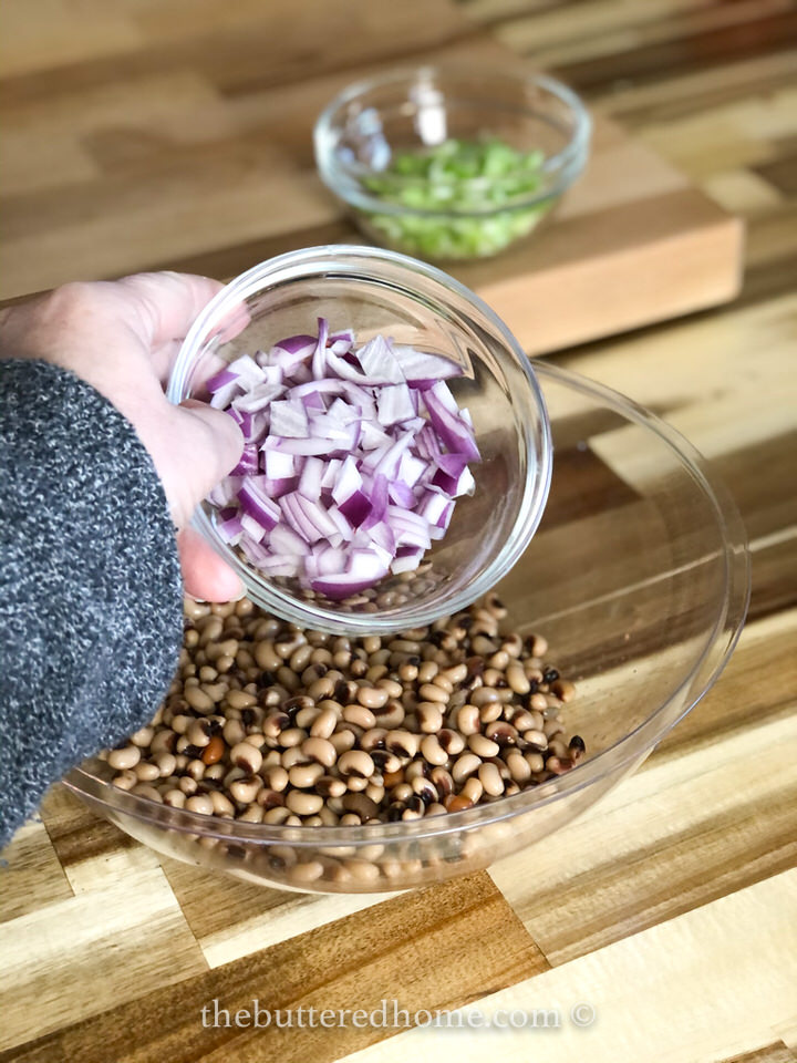 adding chopped onions to black eyed peas