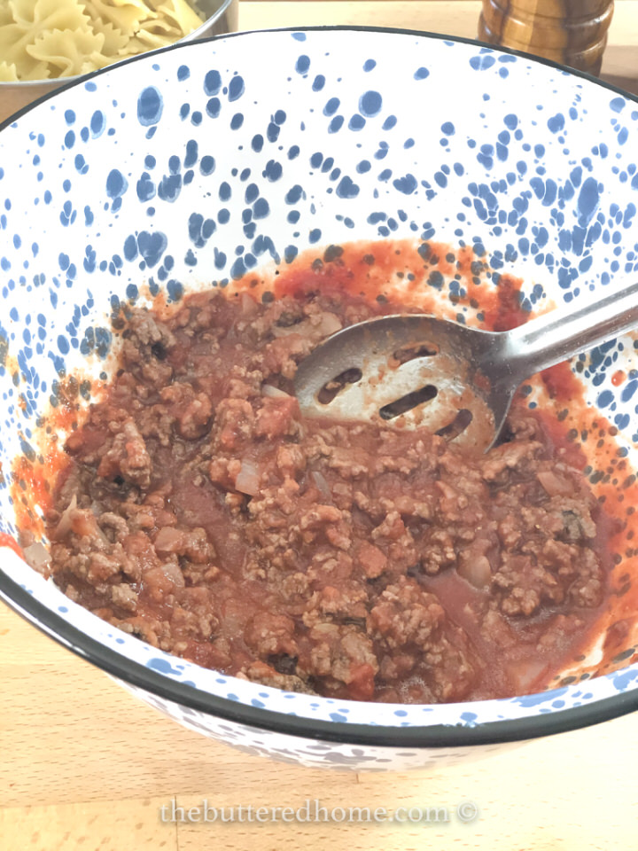 mixing cooked beef with tomato sauce