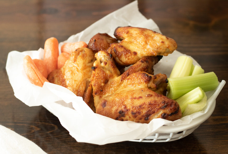 full photo of basket of chicken wings on brown table