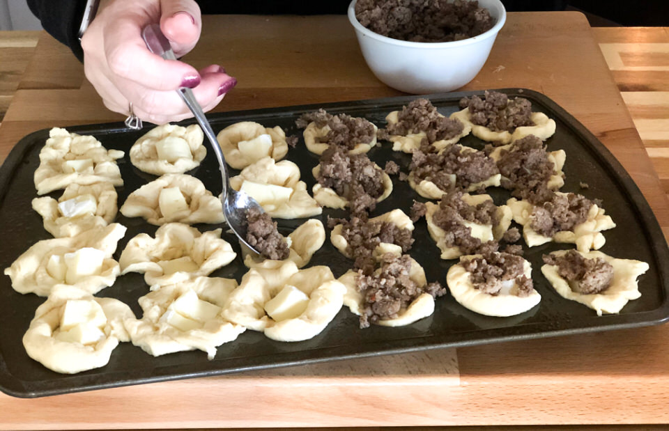 adding spoons of cooked sausage to brie bites