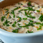 bowl of sausage dip with green onions on top