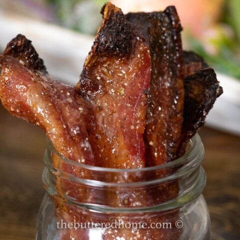 tops of candied maple bacon sitting in a jar