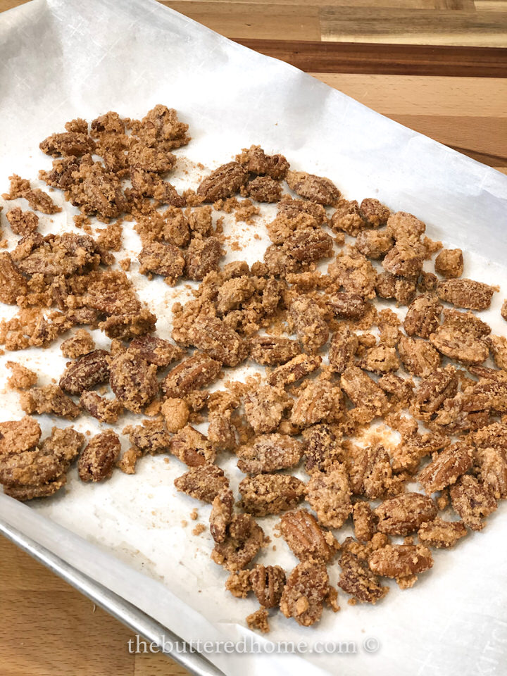 candied pecans cooling on a parchment lined sheet pan