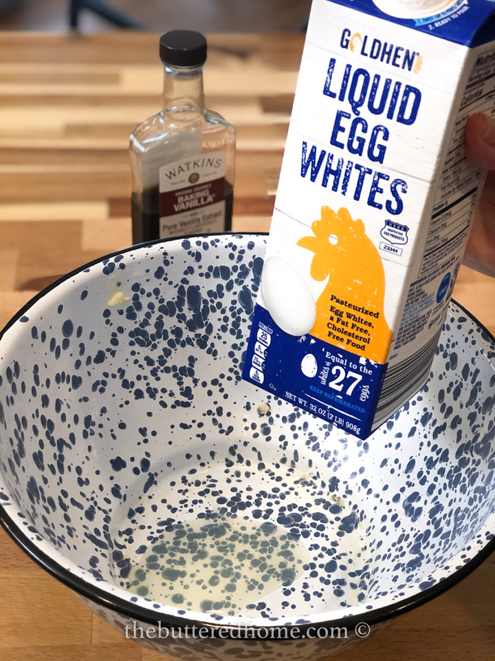 adding liquid egg white to a large blue and white mixing bowl.