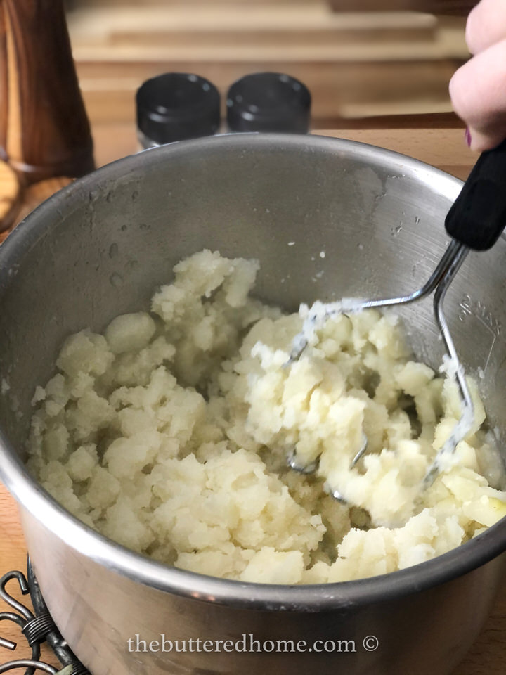 mashing the cooked potatoes