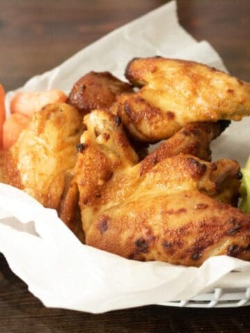 chicken wings on parchment in a serving basket with veggies