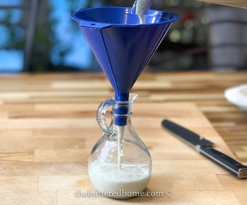 using a blue funnel to put dressing into a decanter