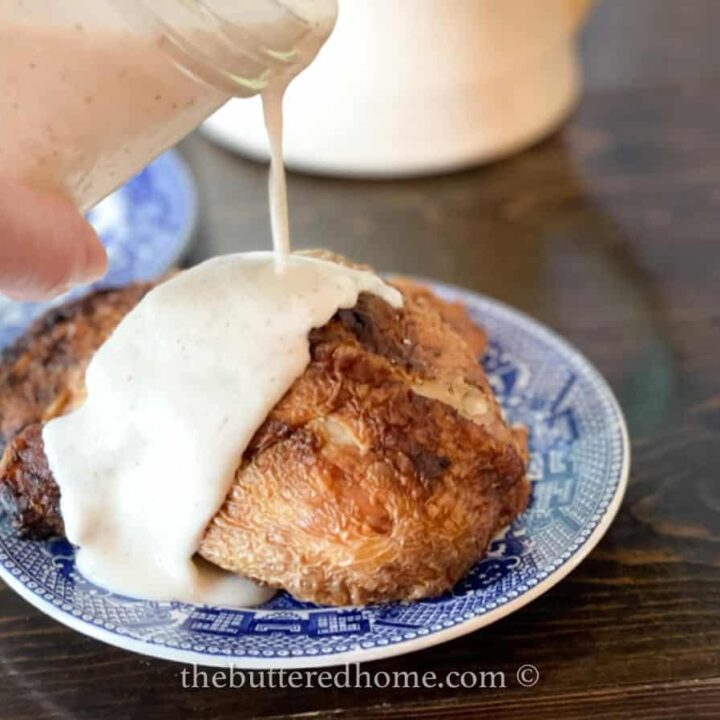 pouring white bbq sauce over chicken half on a blue and white plate