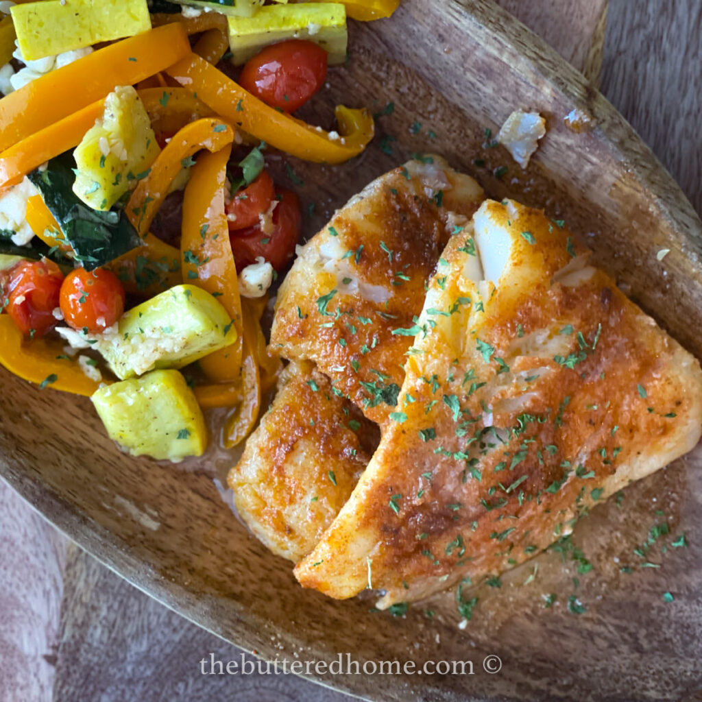 cooked fish on a wooden plate garnished with parsley