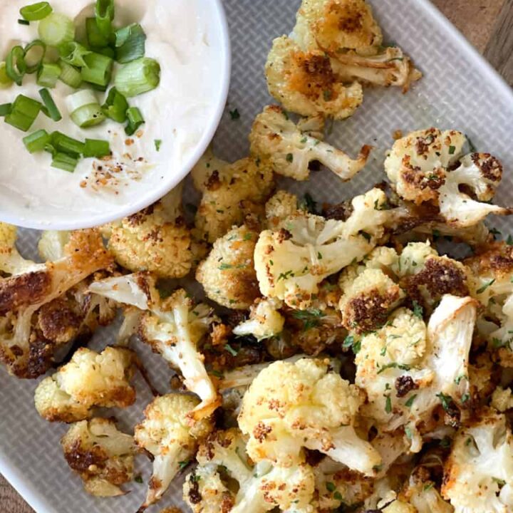 roasted cauliflower and a dip with green onions on a grey platter