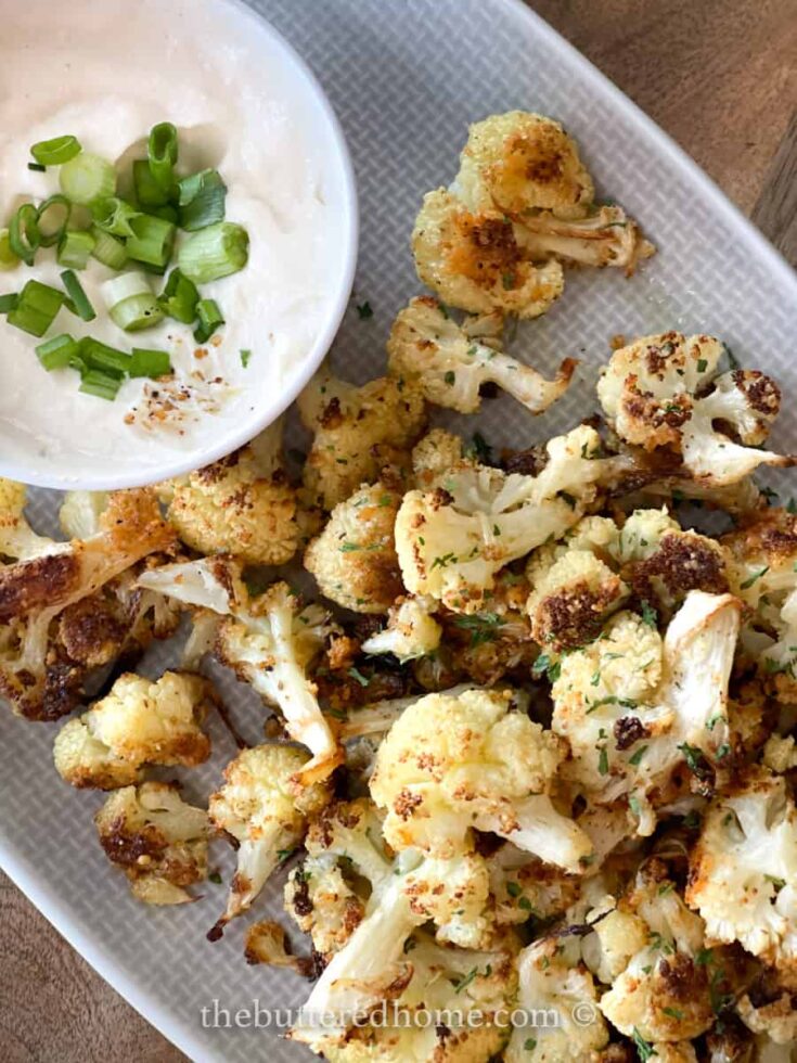 roasted cauliflower and a dip with green onions on a grey platter