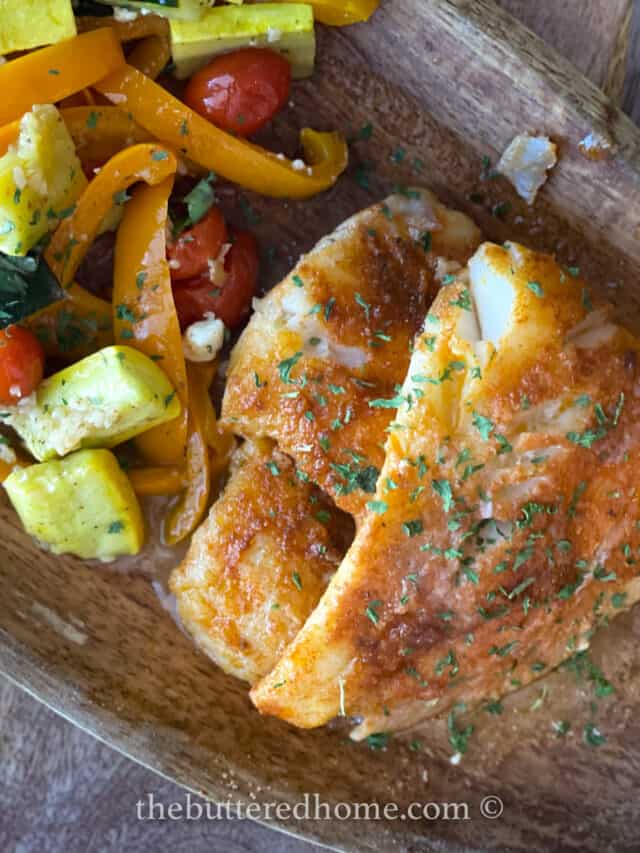 cooked fish on a wooden plate garnished with parsley
