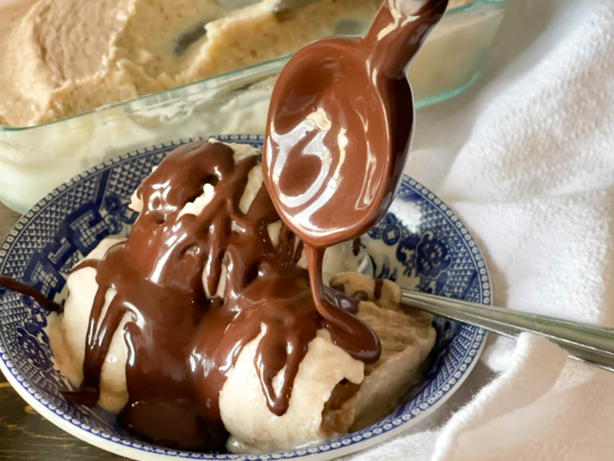 large spoon drizzling chocolate sauce over ice cream