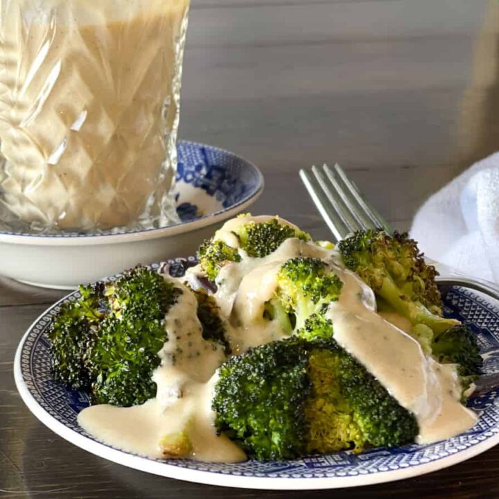 a serving of broccoli with cheese on a blue and white plate