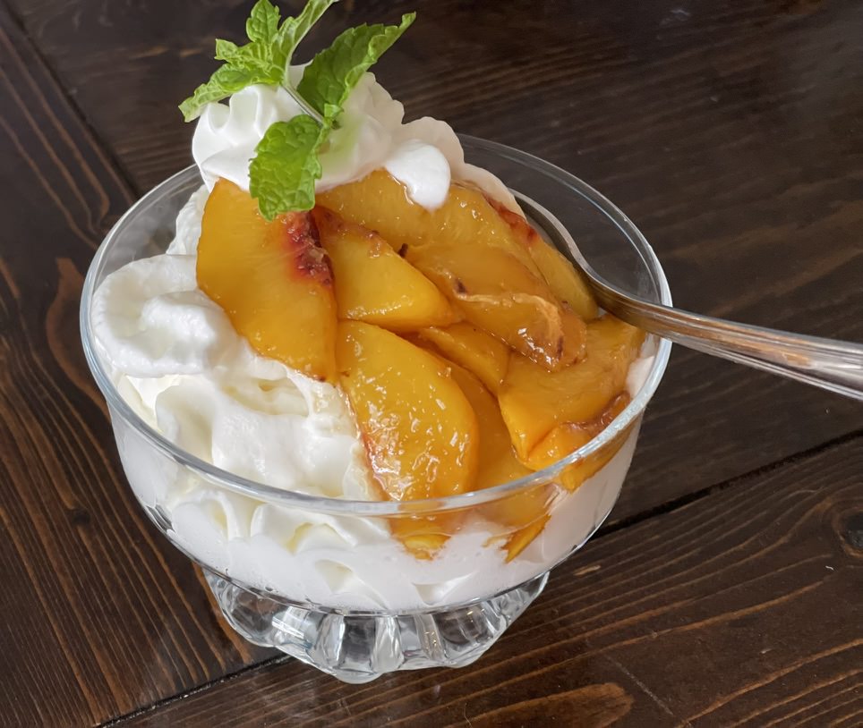 peaches sitting in cream in a glass dish