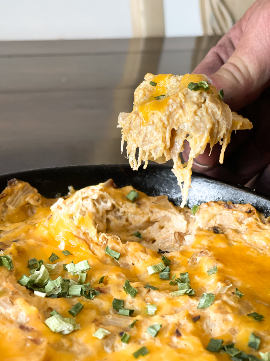 a scoop of dip on a chip above a cast iron skillet