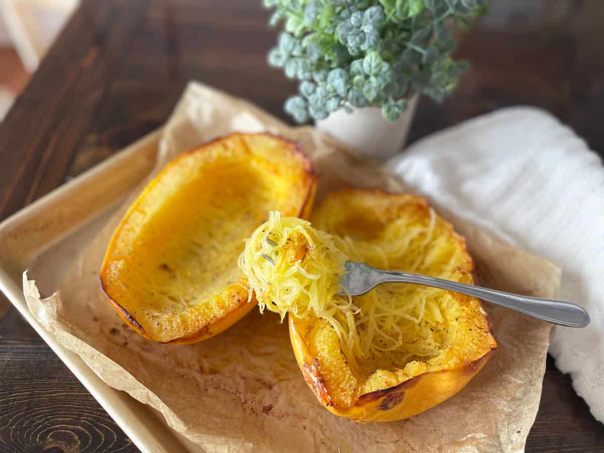 spaghetti squash on a baking sheet with a fork full of squash on top.