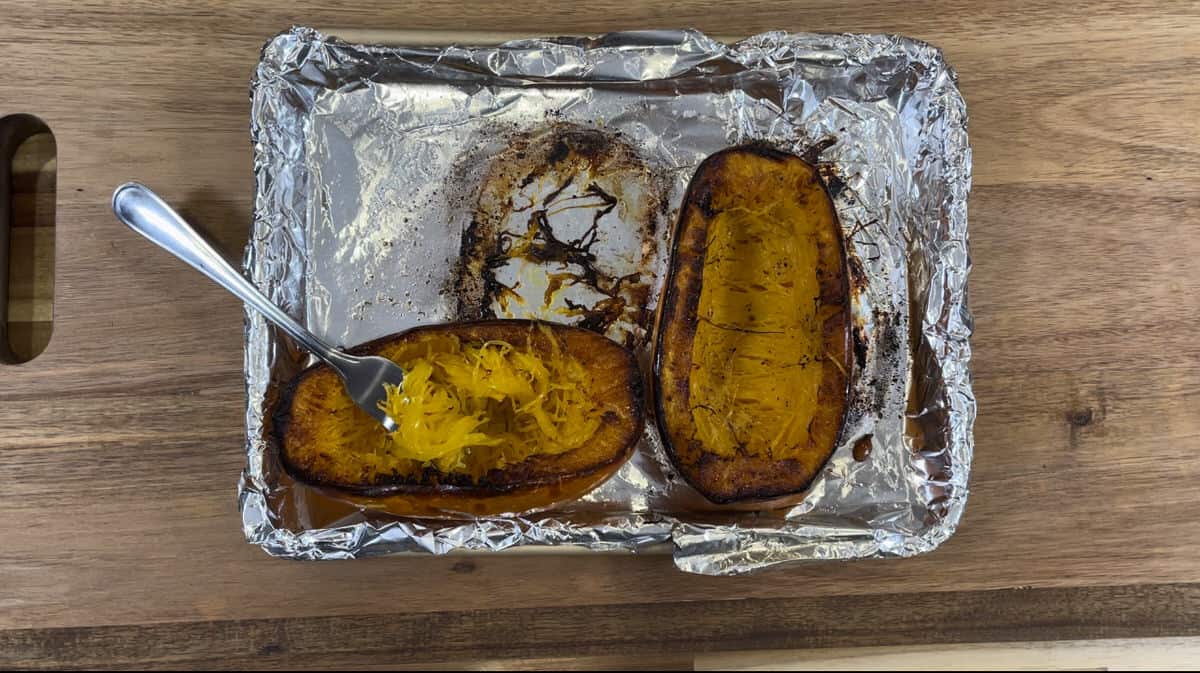 roasted squash on a foil lined pan with a fork to pull out squash.