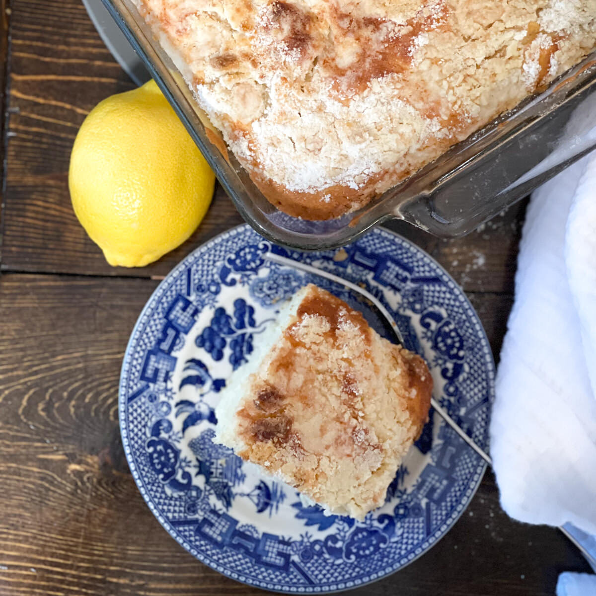 lemon cream cheese coffee cake on a blue and white plate with a lemon next to it.