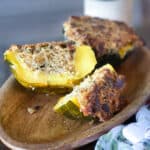 acorn squash that has been stuffed and cut on a brown platter.