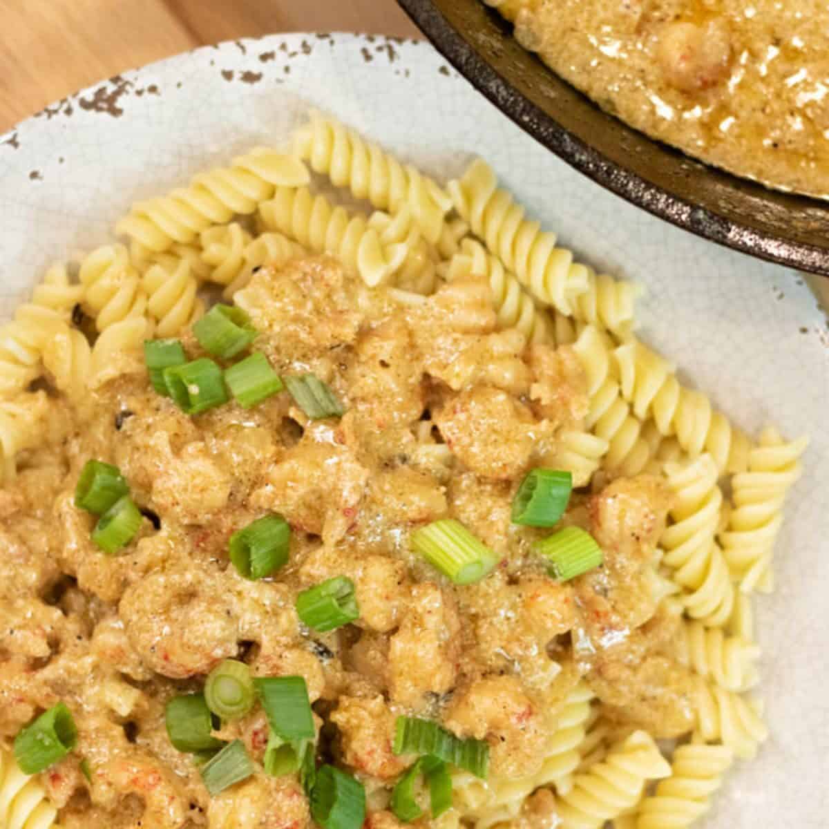 creamy crawfish over spiral pasta on a grey plate.