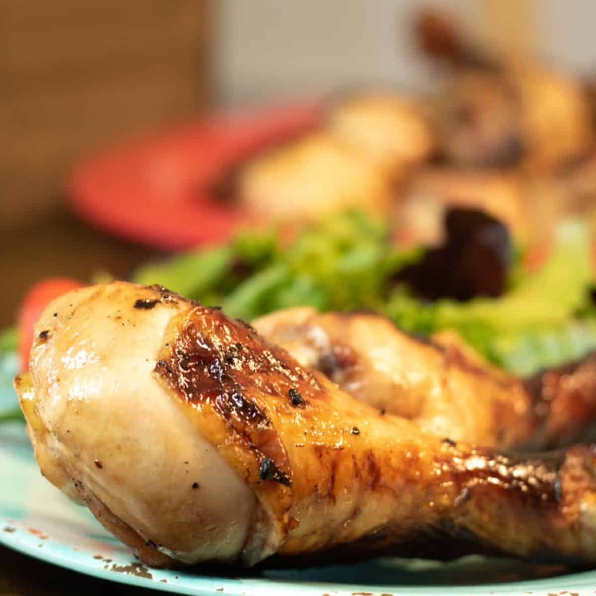 two drunken bbq chicken legs on a blue plate